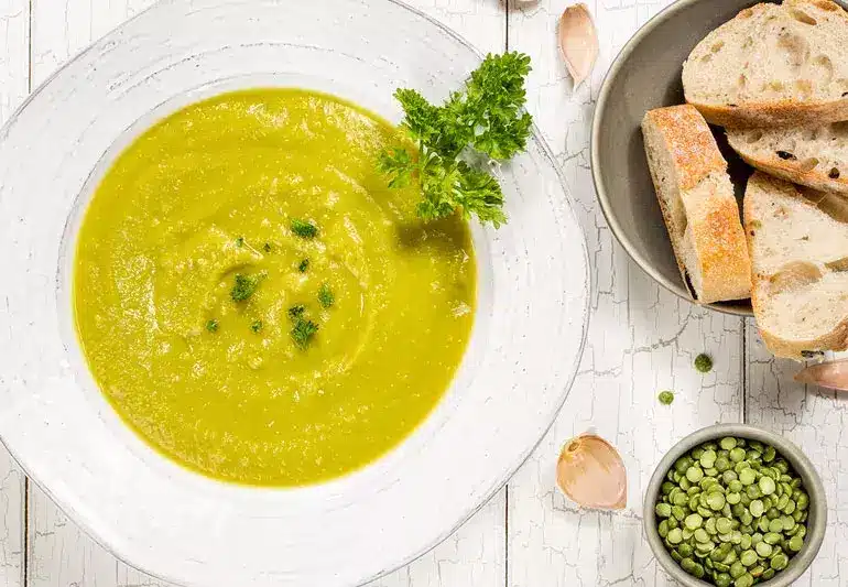 a bowl of soup next to a bowl of bread